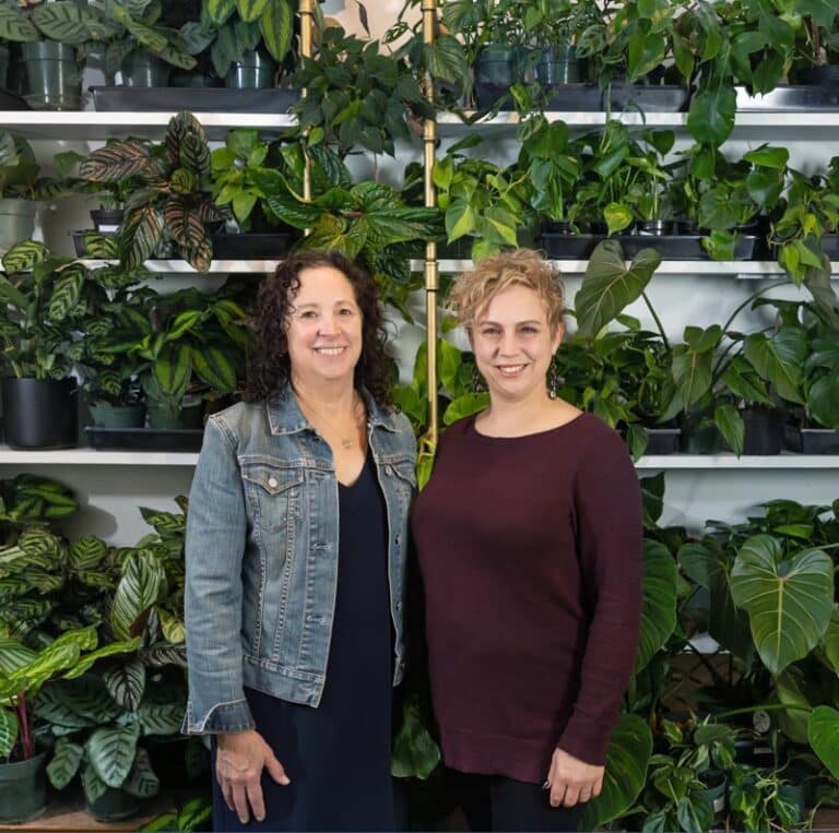 Dianna and Jill standing by shelves of plants